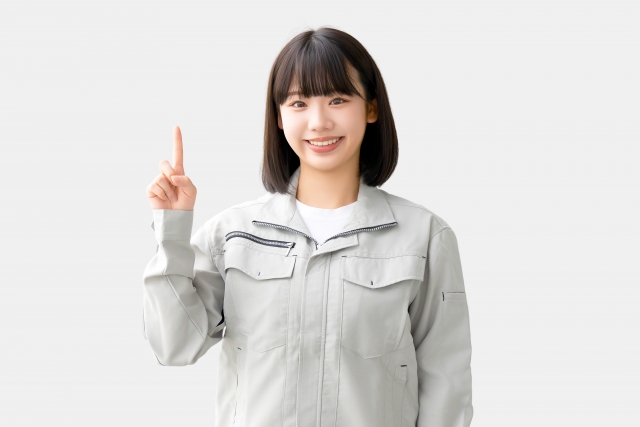 作業服を着た女性が微笑んで指差し